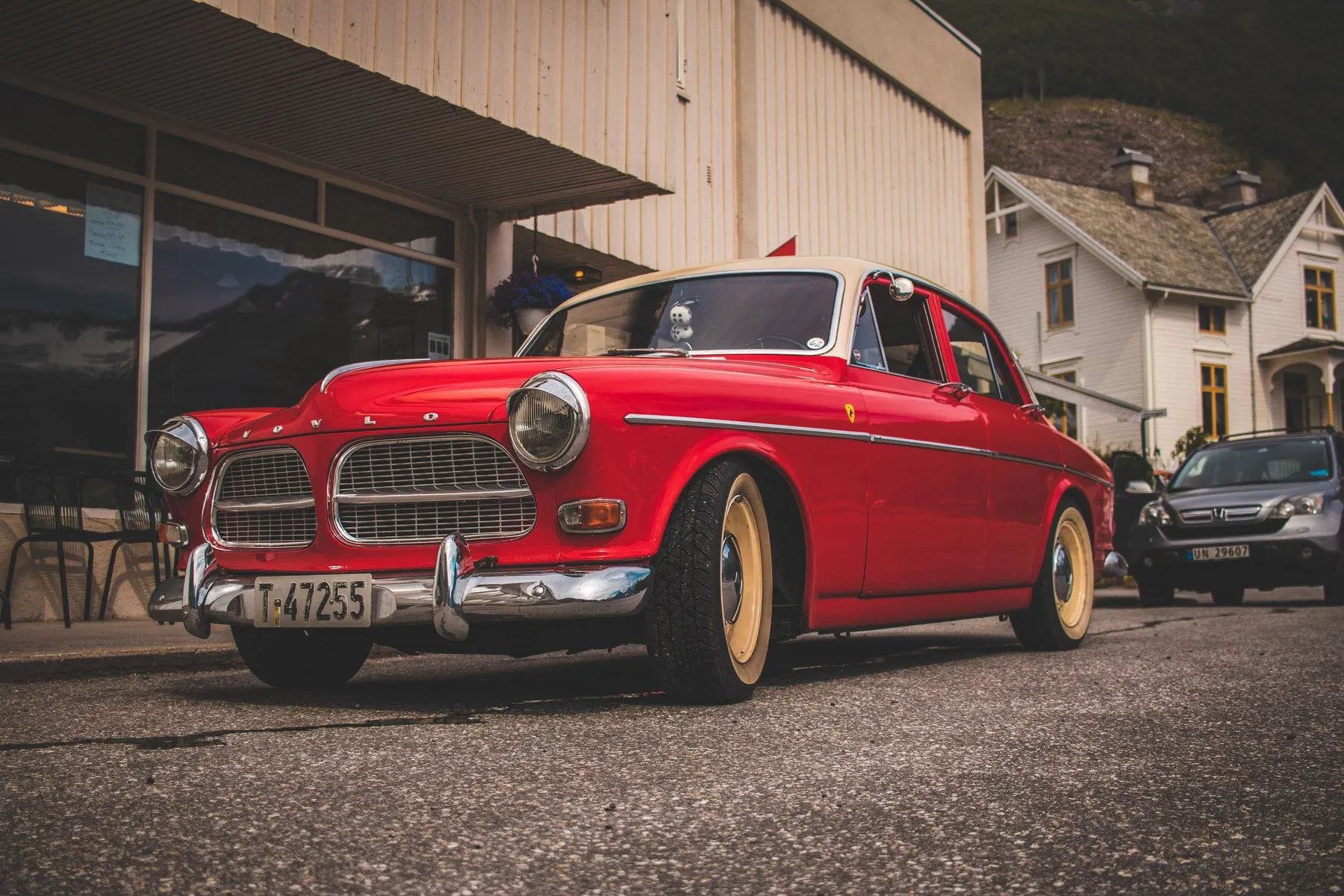 Red 1967 Volvo Amazon parked in front of a wooden building