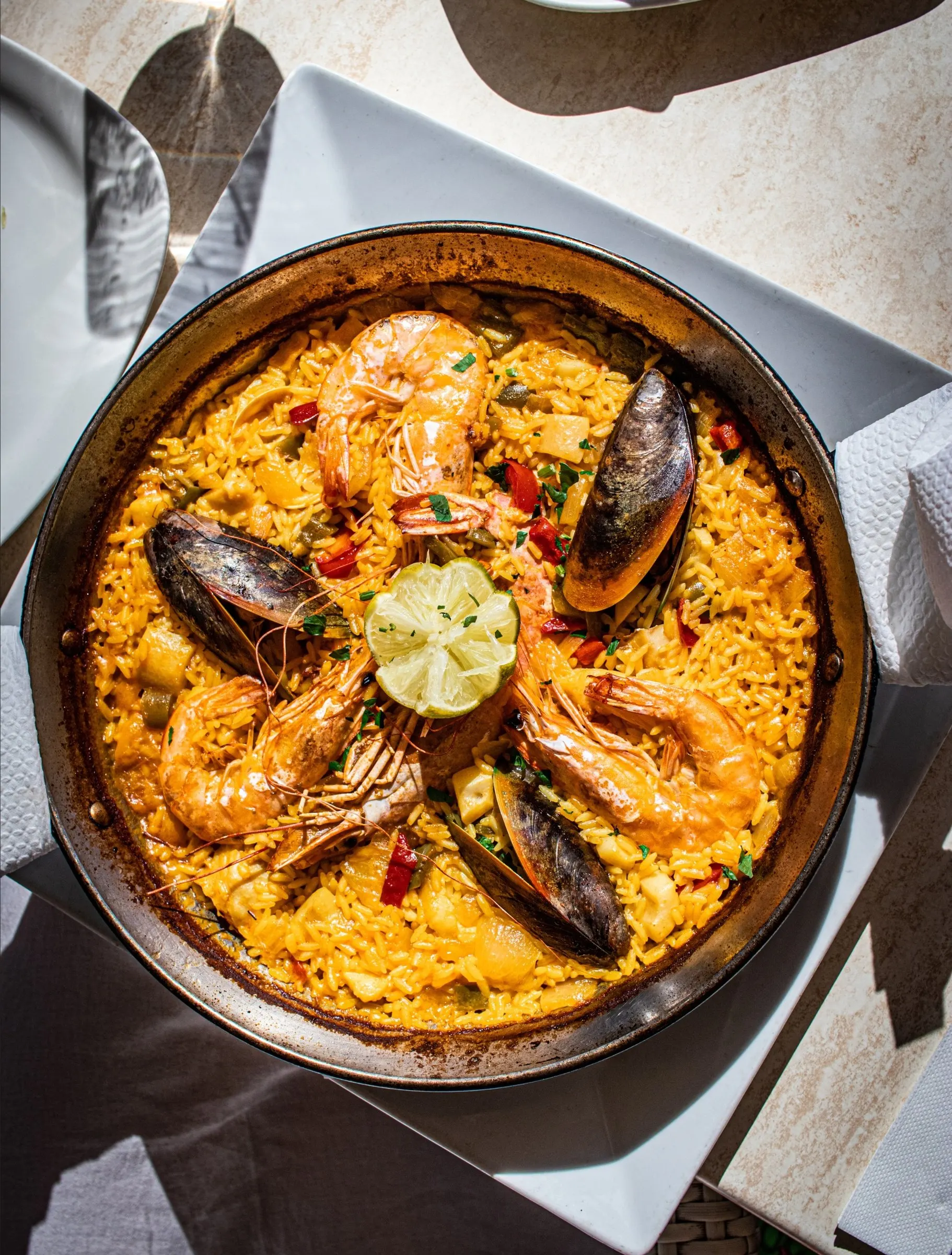 Paella with prawns, mussels and a lime wedge, shot from above